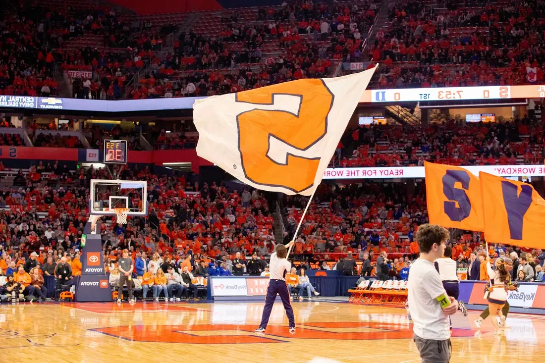 Student waving a Syracuse University flag during a game in the JMA Wireless Dome.